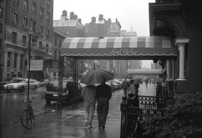 People walking on footpath in city during rainy season