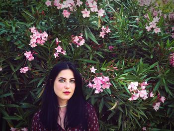 Portrait of beautiful young woman against plants