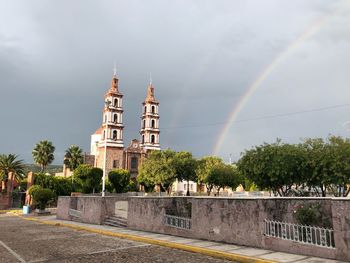 Panoramic view of rainbow over building against sky