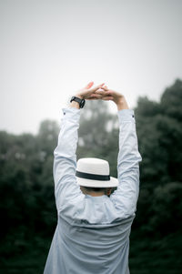 Rear view of man holding umbrella standing against sky