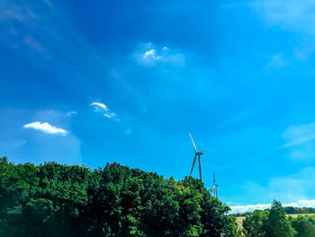 Low angle view of wind turbines against sky
