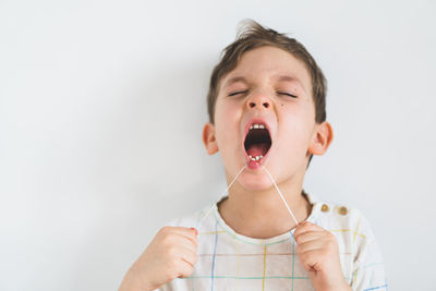 Cute boy pulling loose tooth using a dental floss. process of removing a baby tooth.