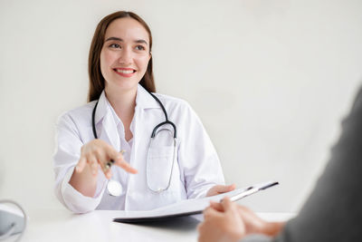 Portrait of doctor holding stethoscope against white background