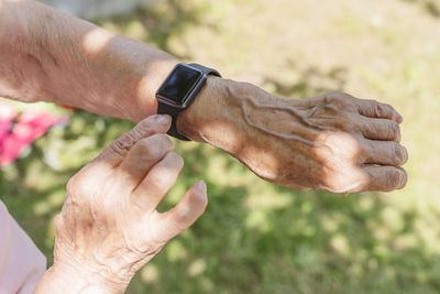 Hands of senior woman wearing smart watch on sunny day