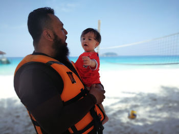 Man carrying baby girl at beach