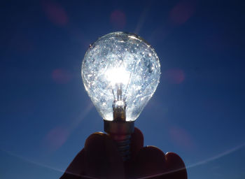 Low angle view of illuminated light bulb against sky