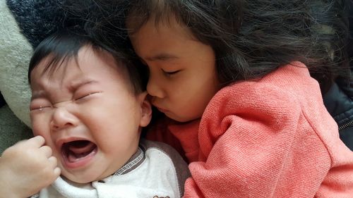 Close-up of cute girl with crying brother at home