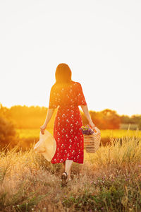 Rear view of woman standing on field against clear sky