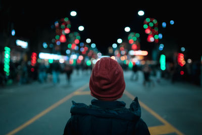 Rear view of person on illuminated street in city at night