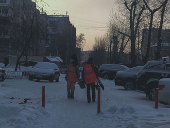 Snow covered street by buildings in city