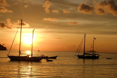 Sailboats in sea against sky during sunset