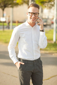 Portrait of young man talking on smart phone while standing in city