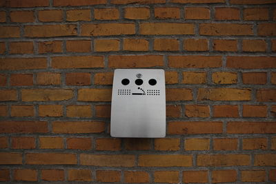 Silver cigarette dustbin mounted on brick wall