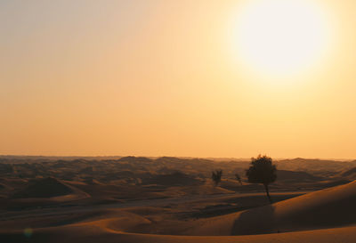 Scenic view of desert against clear sky during sunset