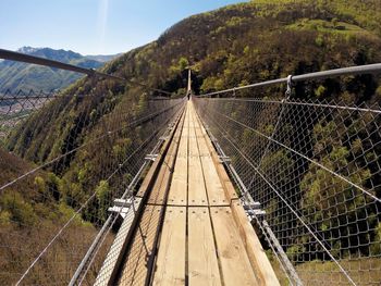 Footbridge over mountain against sky