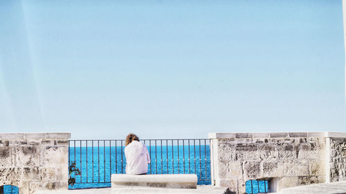 Rear view of woman looking at sea against clear sky