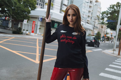 Portrait of young woman standing on sidewalk in city