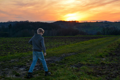 A boy runs in nature by sundown