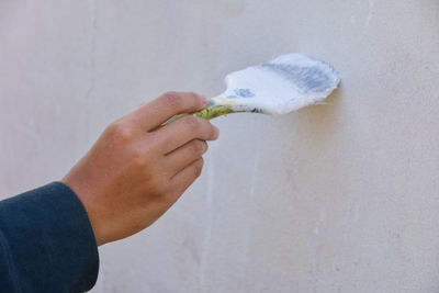 Person holding ice cream cone against wall at home