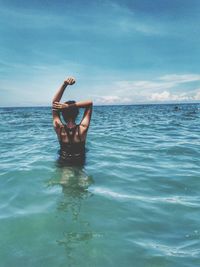 Rear view of woman in sea against sky