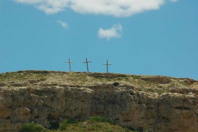 Low angle view of crosses on rock formation against sky