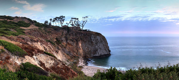 Scenic view of cliff by sea against sky