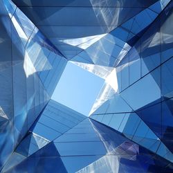 Low angle view of glass building against blue sky