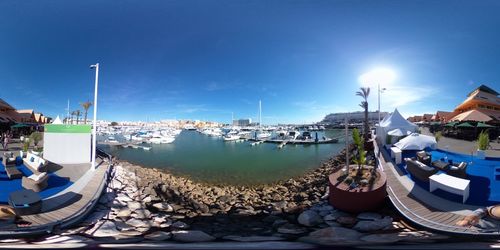 Sailboats moored at harbor against blue sky