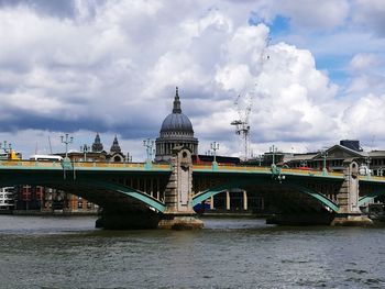 Bridge over river against cloudy sky