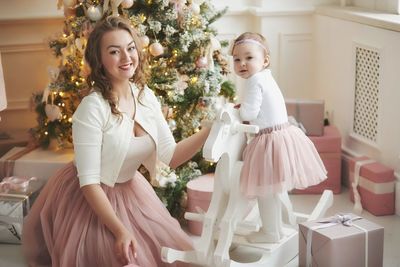 Portrait of smiling mother and daughter against christmas tree