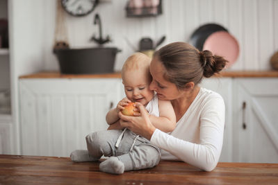 Side view of mother and daughter sitting on bed at home