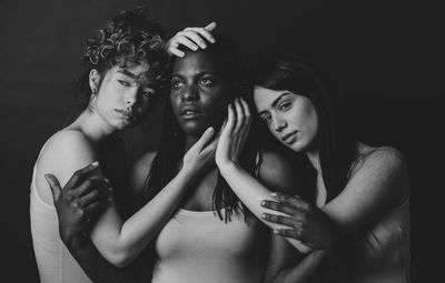 Women standing against black background