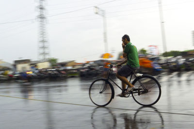 Man riding bicycle on wet road