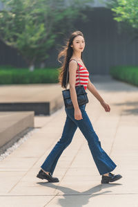 Portrait of young woman standing on footpath