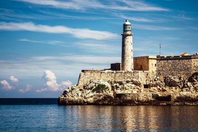 Lighthouse by sea against sky