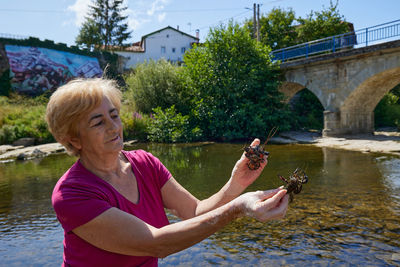 Woman fishing for a crayfish and showing it in her hands