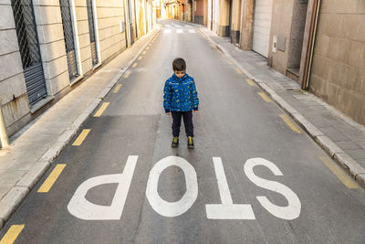 Boy standing by stop text on road