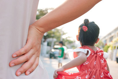 Close-up midsection woman with hand on hip standing by girl on street