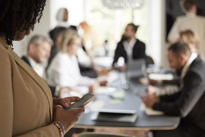 Woman using cell phone during business meeting