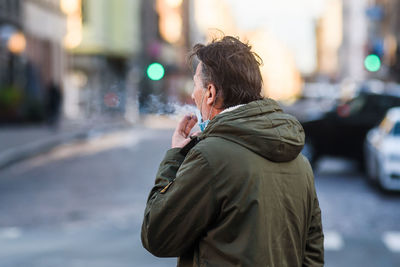 Rear view of woman standing on street in city