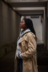 Young woman looking away while standing in snow