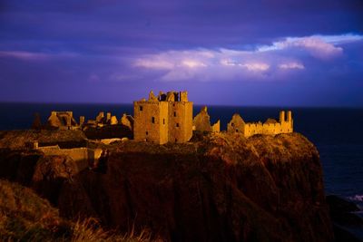 Castle on sea by buildings against sky