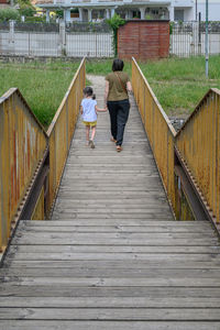 Rear view of women walking on footbridge