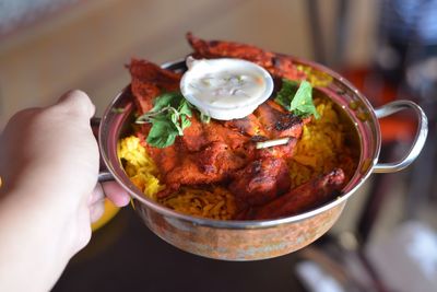 Close-up of hand holding food in bowl at home