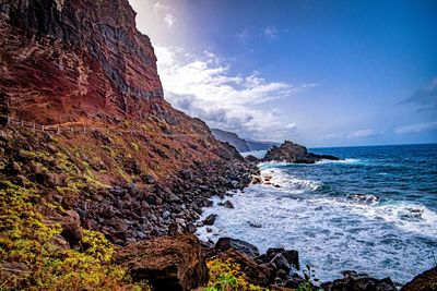 Rock formation on beach against sky