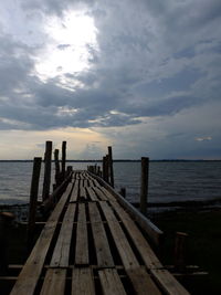 Pier on sea against cloudy sky