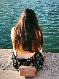 Rear view of woman sitting against lake