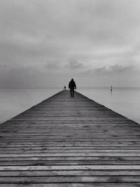 Man walking on jetty against seascape