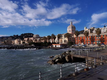 City at waterfront against cloudy sky