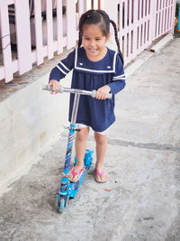 High angle view of smiling girl over push scooter on footpath